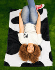 Woman laying on black and white cow print Laze and Graze Beach Towel