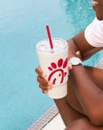 Man sitting by a pool and holding Original Chick-fil-A 24oz Insulated Tumbler with straw
