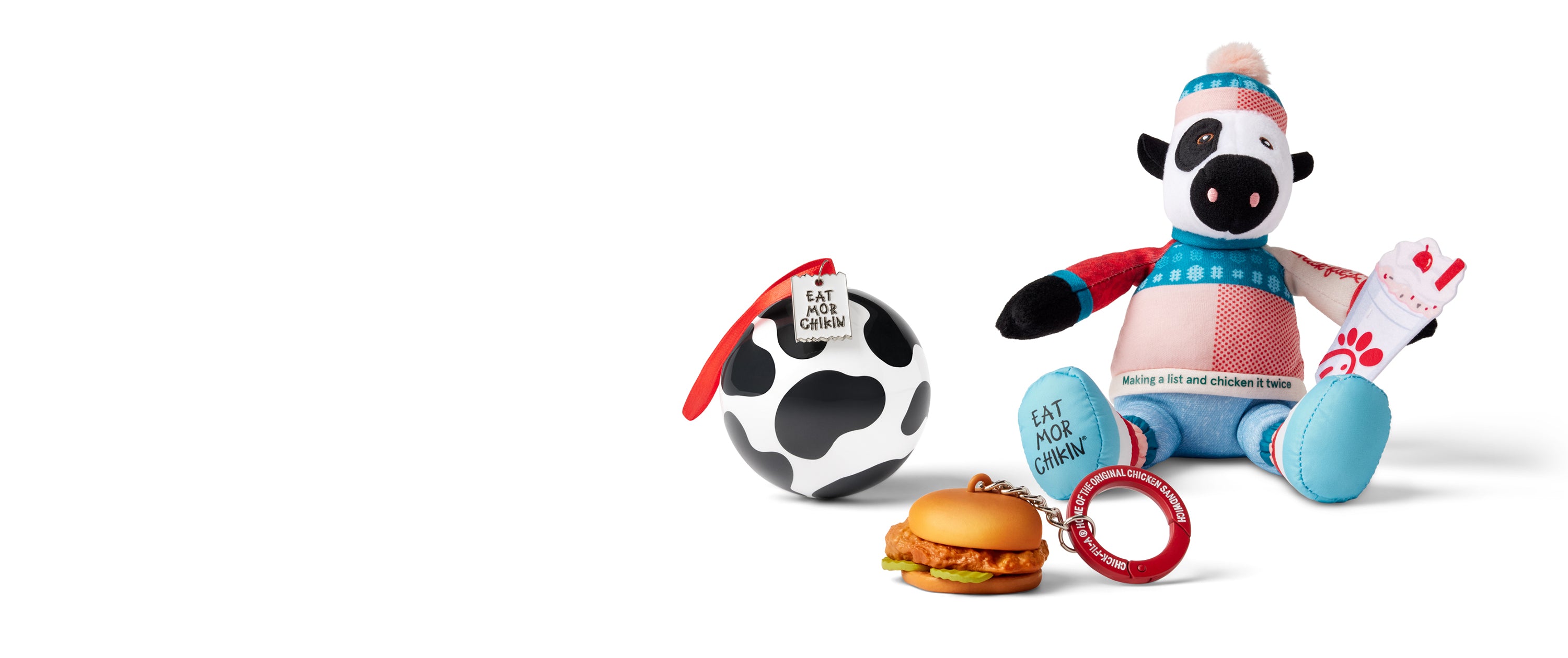 Original Chick-fil-A® Chicken Sandwich keychain, cow print ball ornament, and and cow plush in festive sweater and beanie