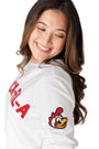 Woman looking down wearing Heritage Doodles Crewneck with the Doodles patch on the sleeve