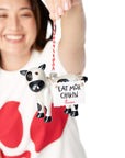 Woman in a Chick-fil-A Logo Print Tee holding a black and white cow ornament wearing a sign that says "EAT MOR CHIKIN"