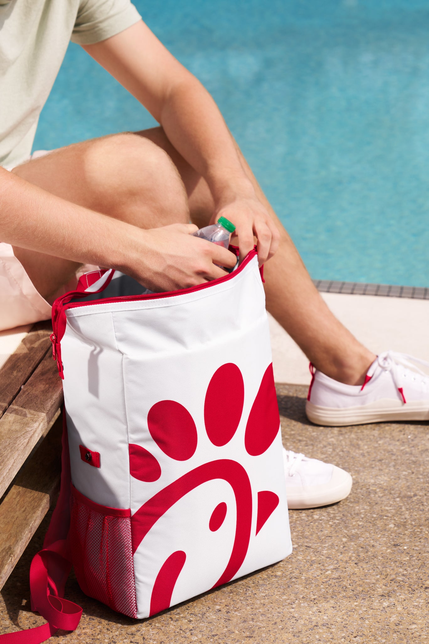 Person placing a bottle in Chick-fil-A Soft Sided Backpack Cooler