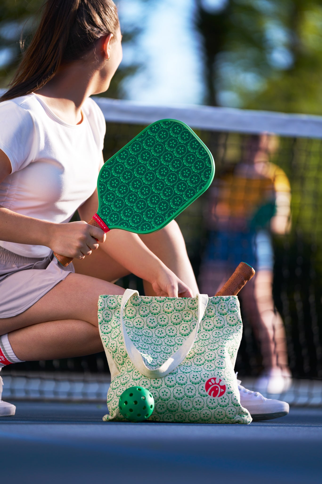Woman on a pickleballcourt with Pickle Pickle™ Pickleball Set including the pickleball paddle, tote bag, and ball