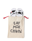 Overhead photograph of Slip On Cow Slides in natural canvas and black "Eat Mor Chikin" drawstring bag