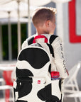 Boy wearing black and white Cow Print Backpack with red strap