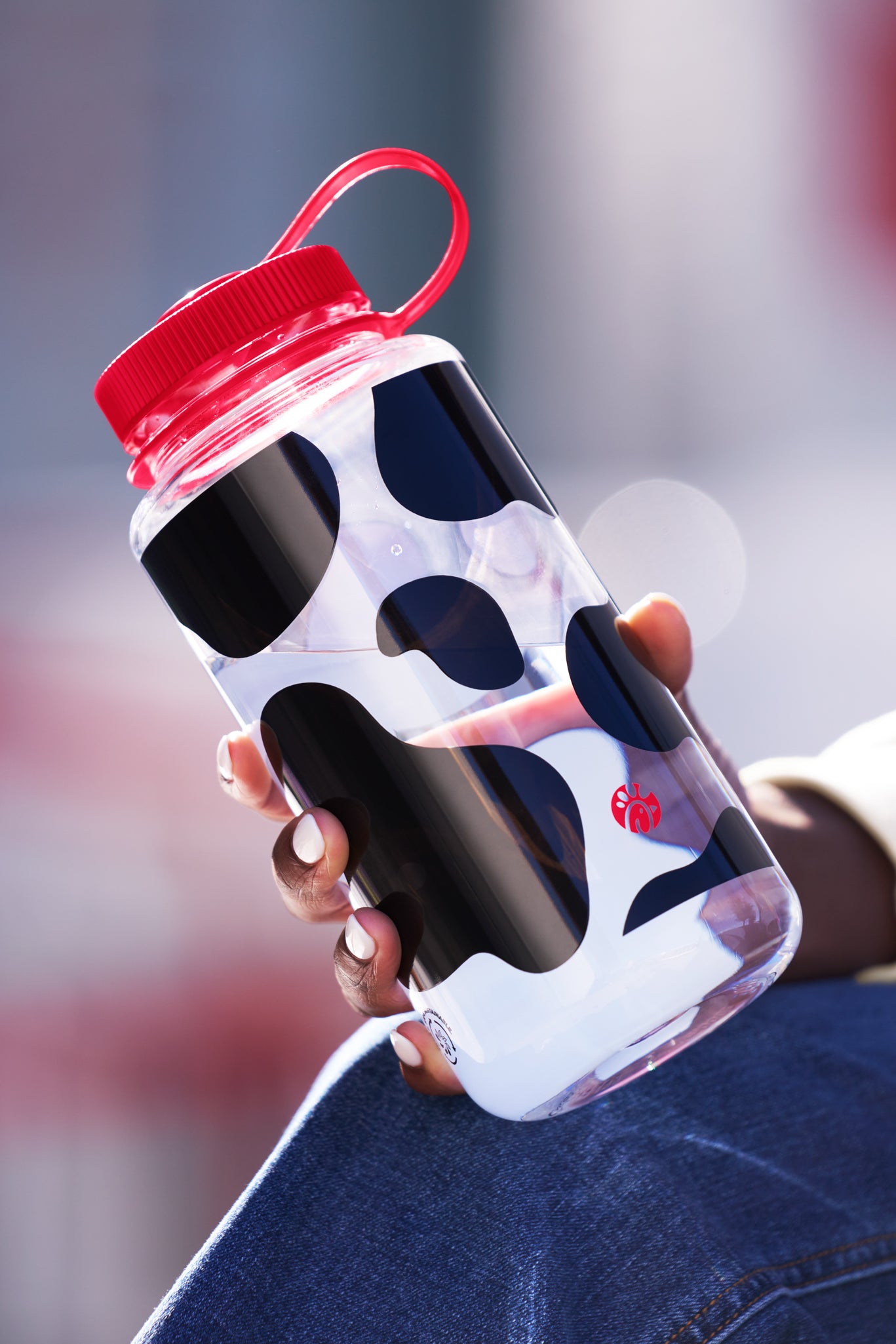 Hand holding Cow Print 32oz Nalgene™ Water Bottle with red lid