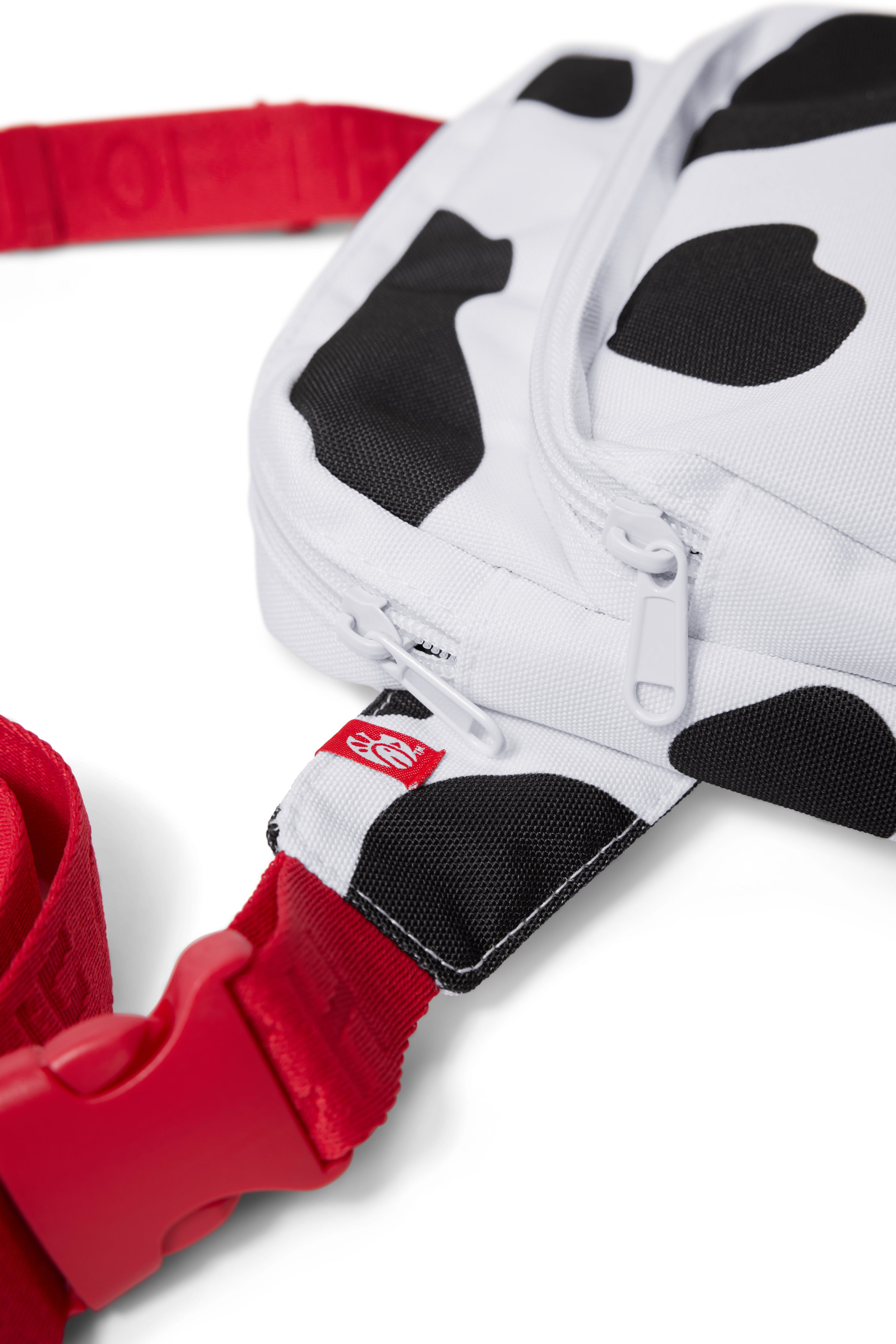 Close-up photograph of black and white Cow Print Belt Bag with red strap