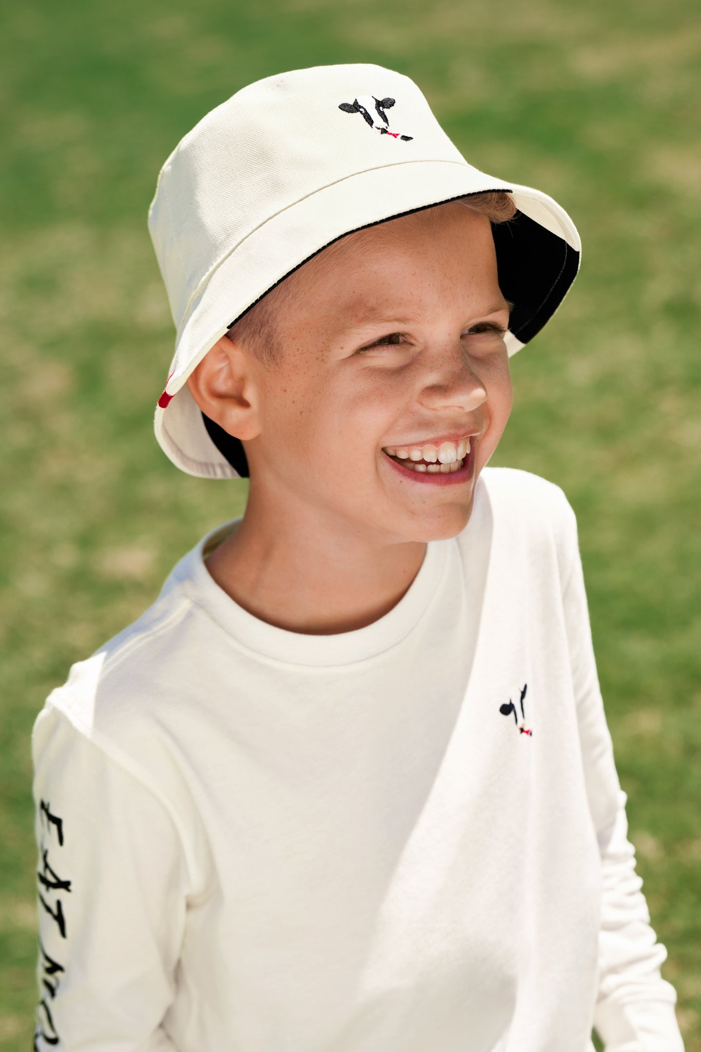 Boy wearing off-white embroidered side of Kids Reversible Cow Print Bucket Hat