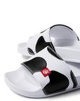 Close up view of Slip On Cow Slides showing black and white cow print pattern and red silicone logo label