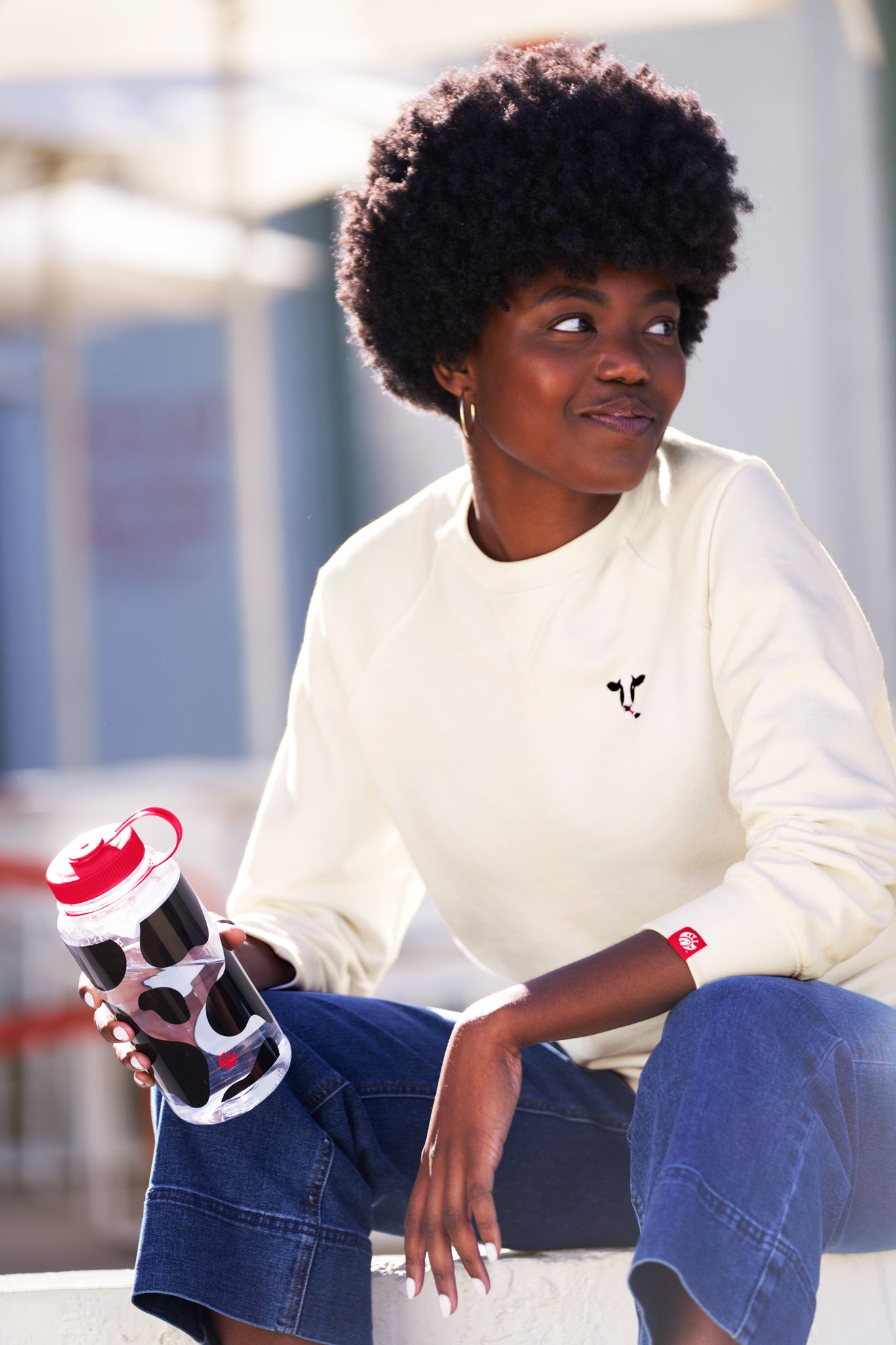 Woman wearing Embroidered Cow Crewneck and holding Cow Print Nalgene