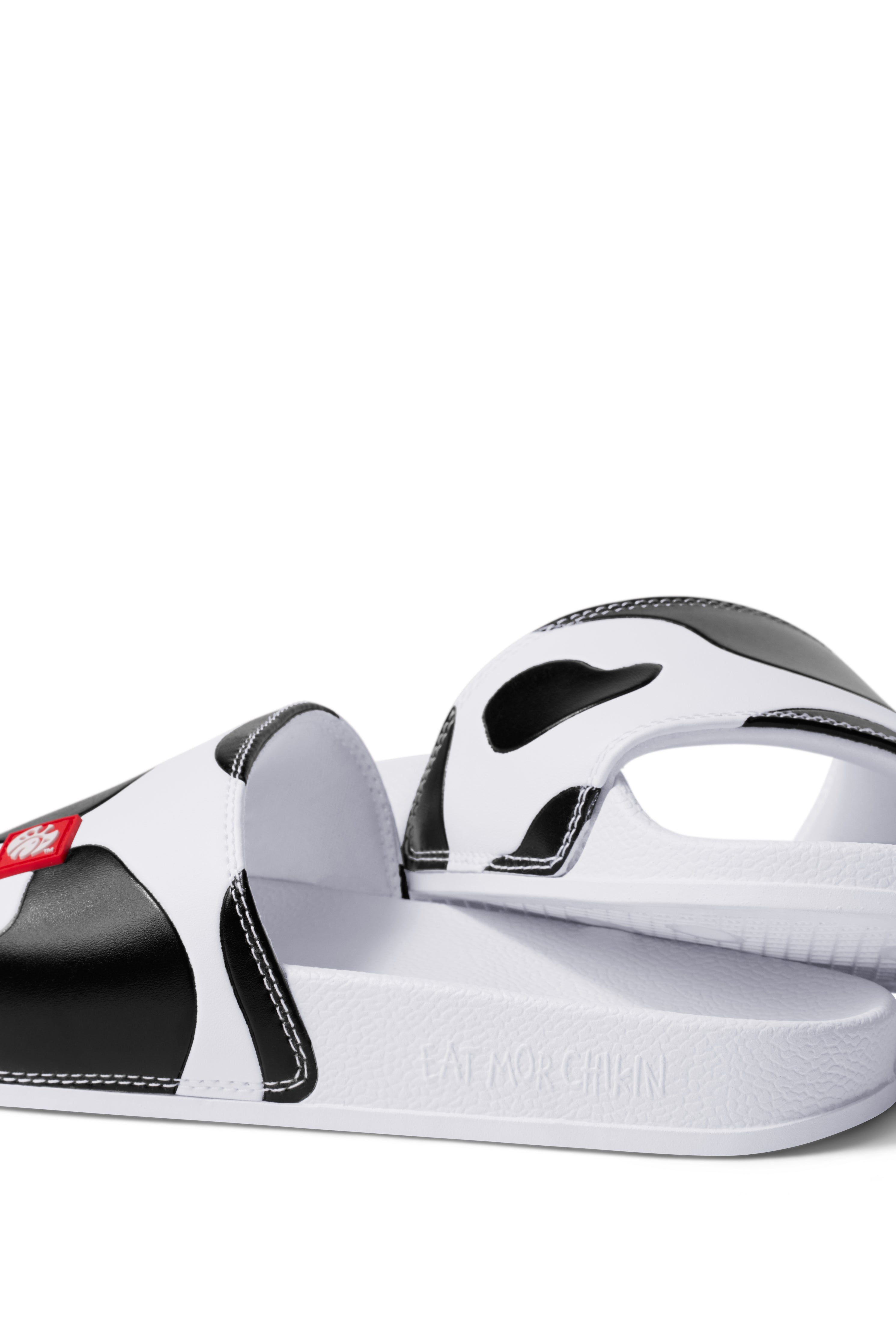 Side view of Slip On Cow Slides showing &quot;Eat Mor Chikin&quot; message on heel of shoe