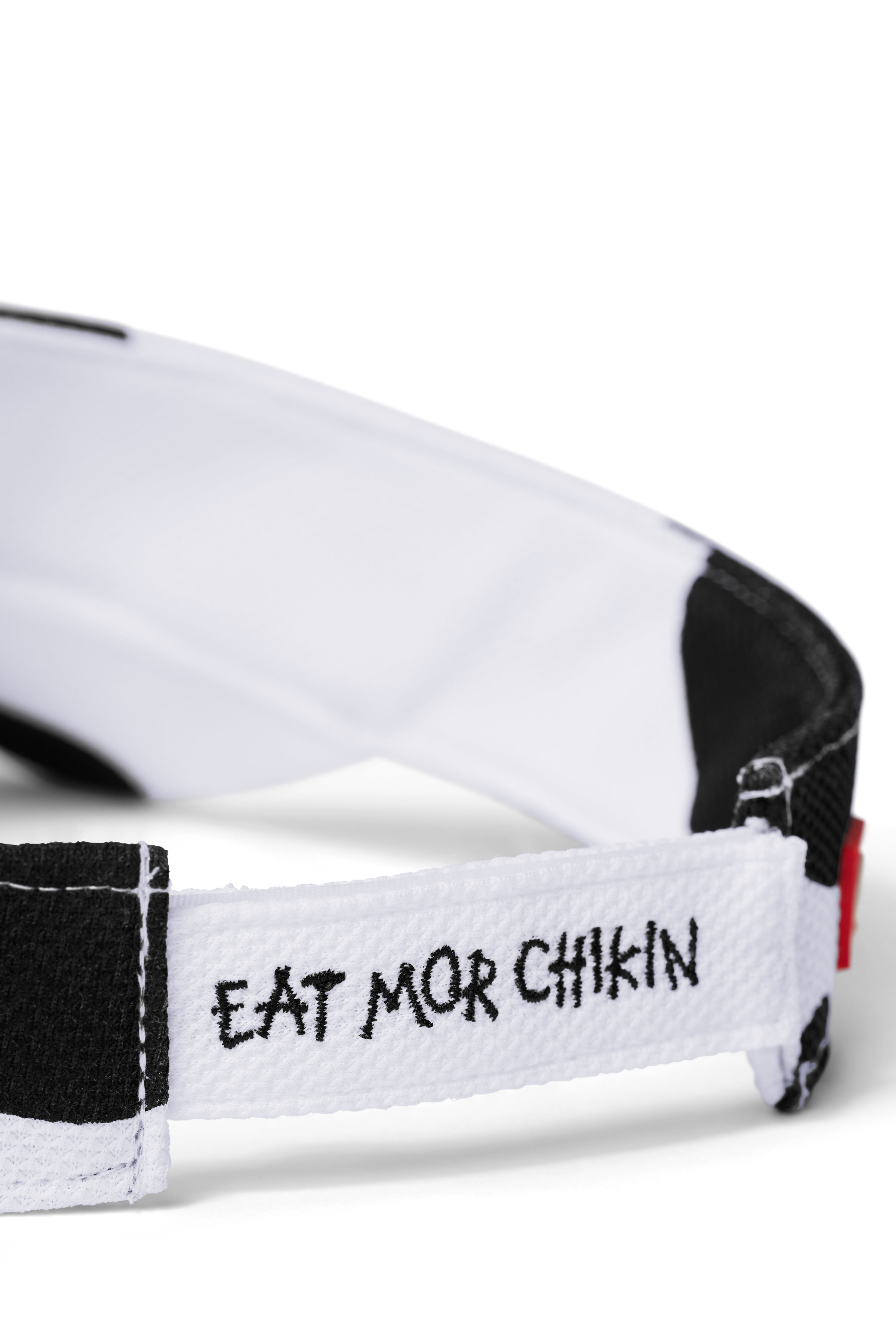 Close up of back of black and white cow print visor with &quot;Eat Mor Chikin&quot; embroidery