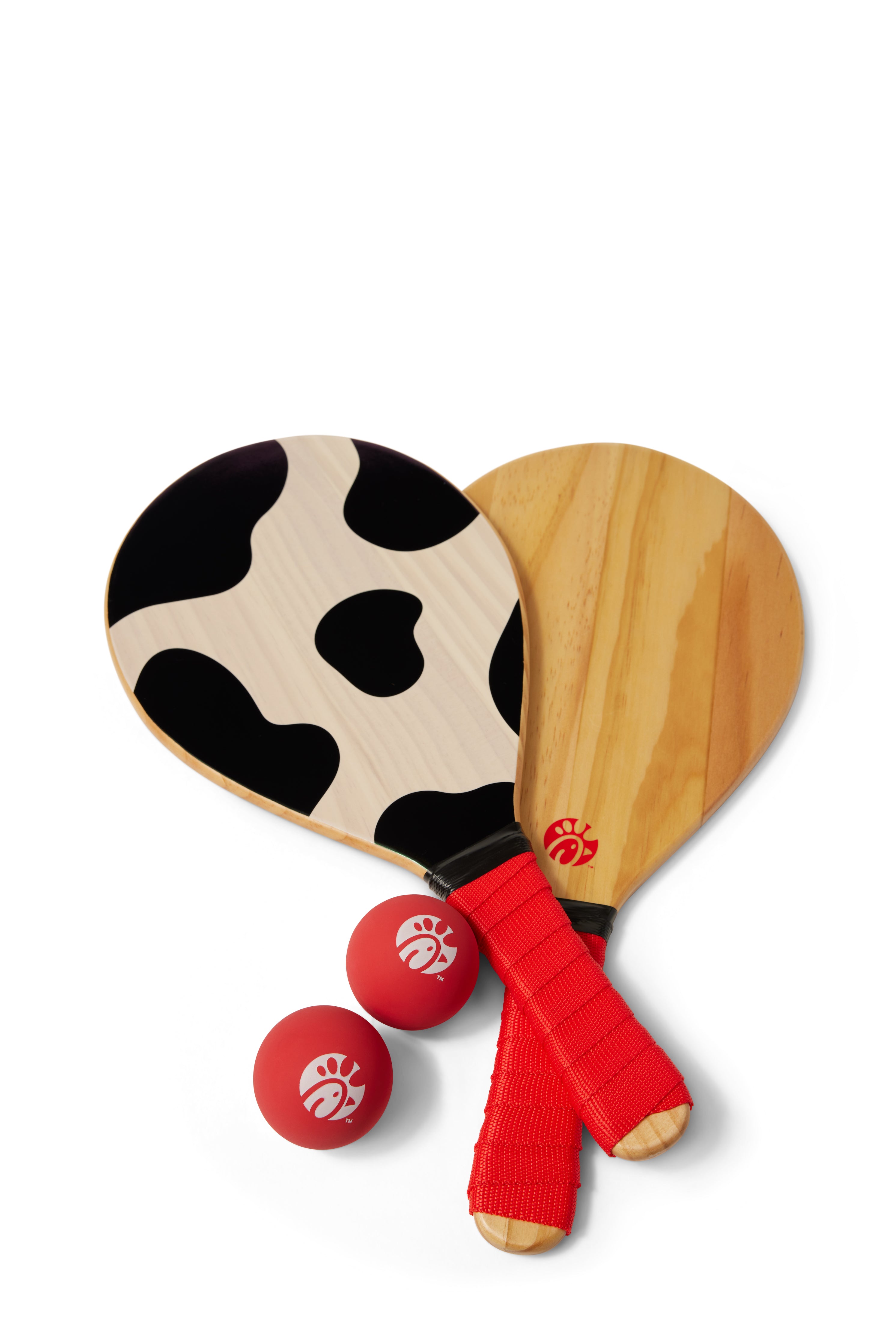 Overhead photograph of wooden Paddle Ball Set including 2 cow print paddles and 2 red balls