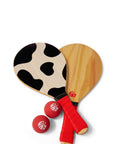 Overhead photograph of wooden Paddle Ball Set including 2 cow print paddles and 2 red balls