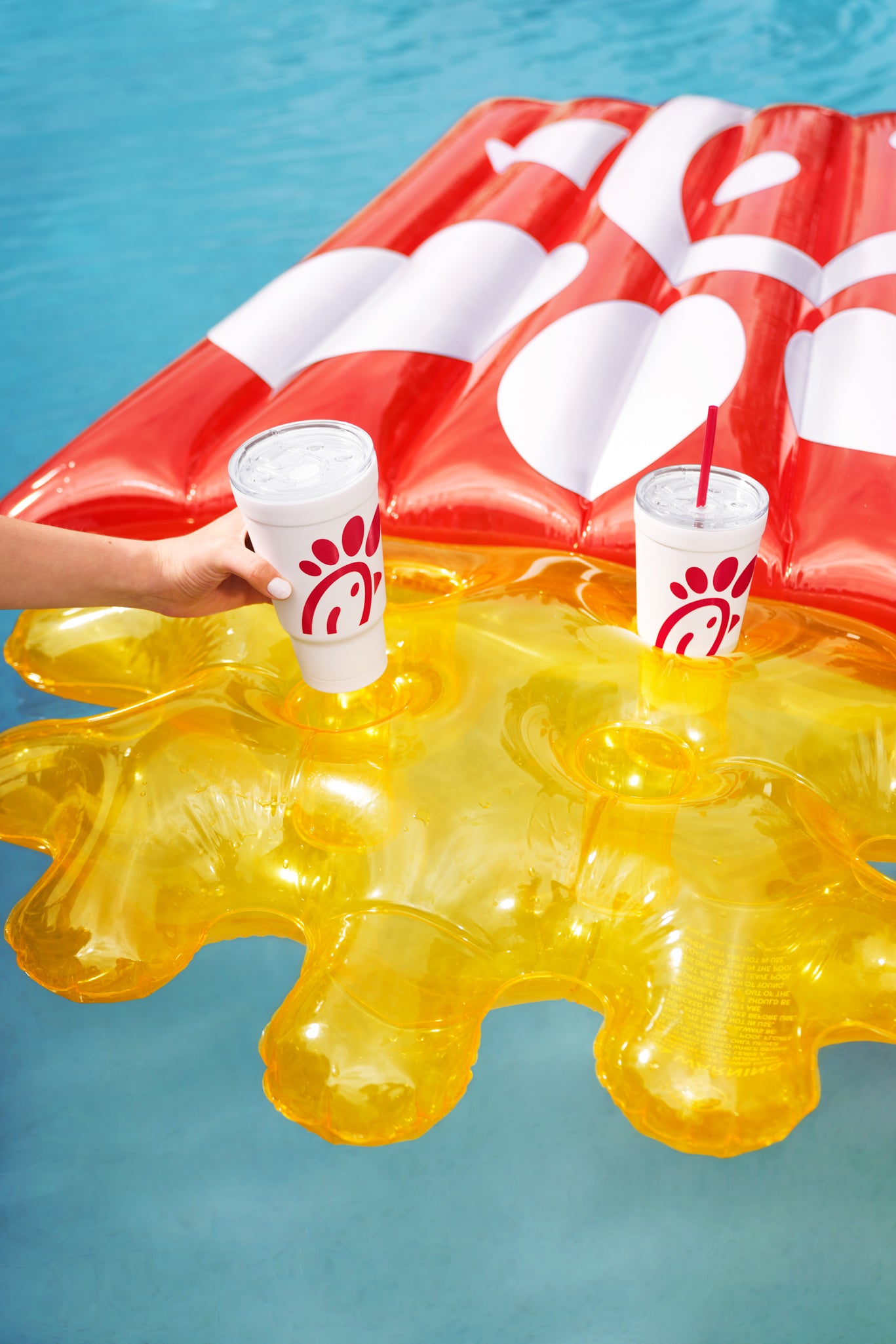 Person placing The Original Chick-fil-A 24oz Insulated Tumbler in Waffle Fry Pool Float cup holders