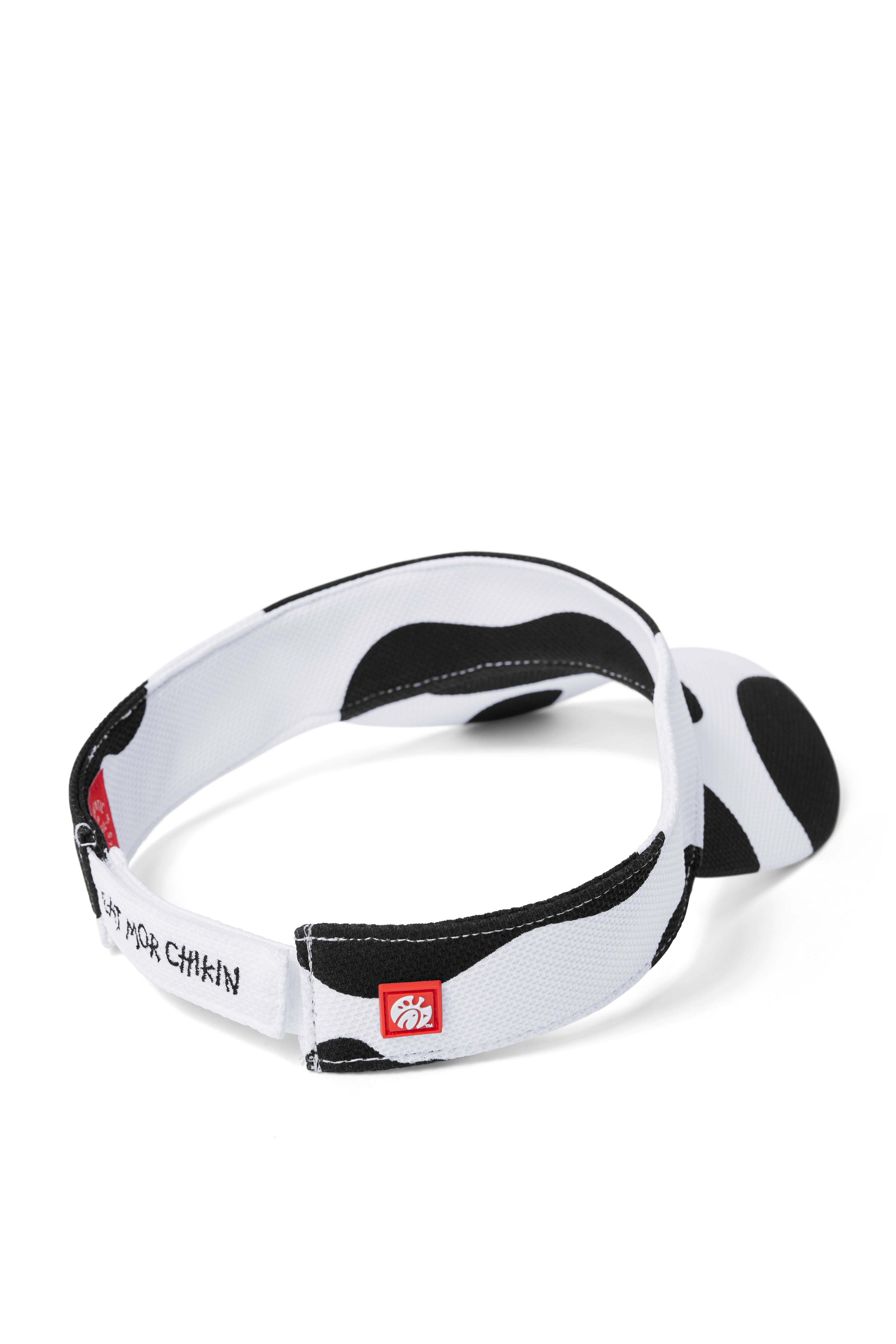 Back view of black and white cow print visor with red logo silicone tag