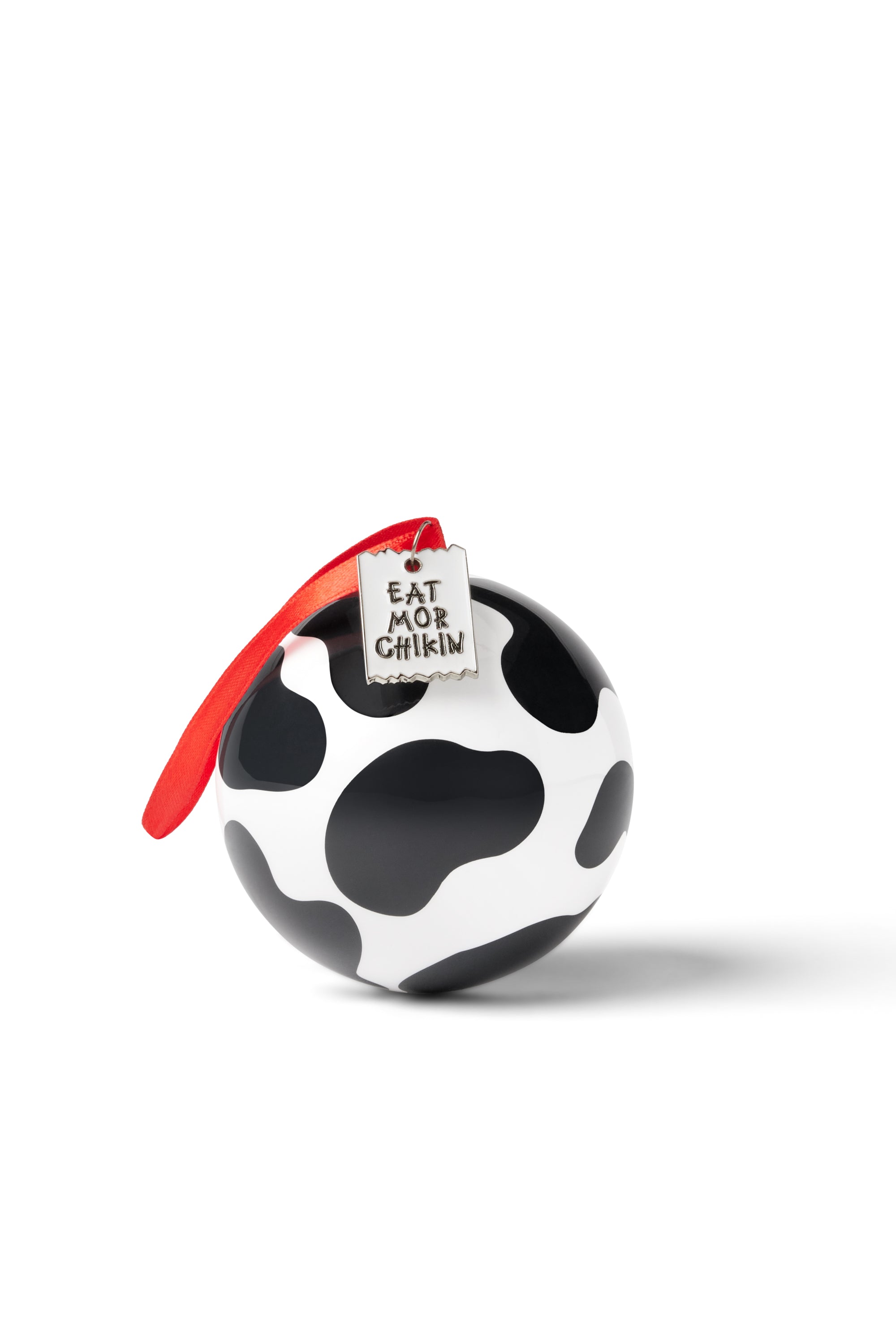 Black and white cow print ball ornament with red ribbon hanging down side and tag on top that says "Eat Mor Chikin"