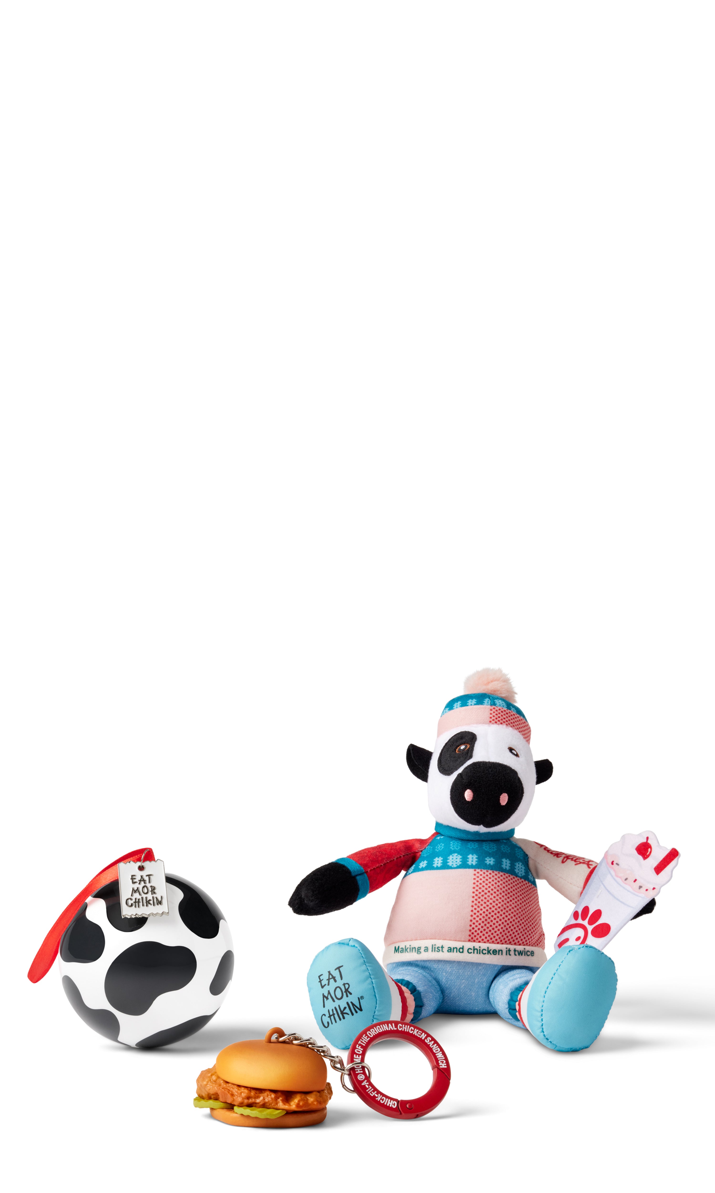 Original Chick-fil-A® Chicken Sandwich keychain, cow print ball ornament, and and cow plush in festive sweater and beanie