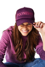 Woman sitting on ground wearing purple Ombre Crewneck with purple/Polynesian Sauce Trucker Hat