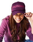 Woman sitting on ground wearing purple Ombre Crewneck with purple/Polynesian Sauce Trucker Hat