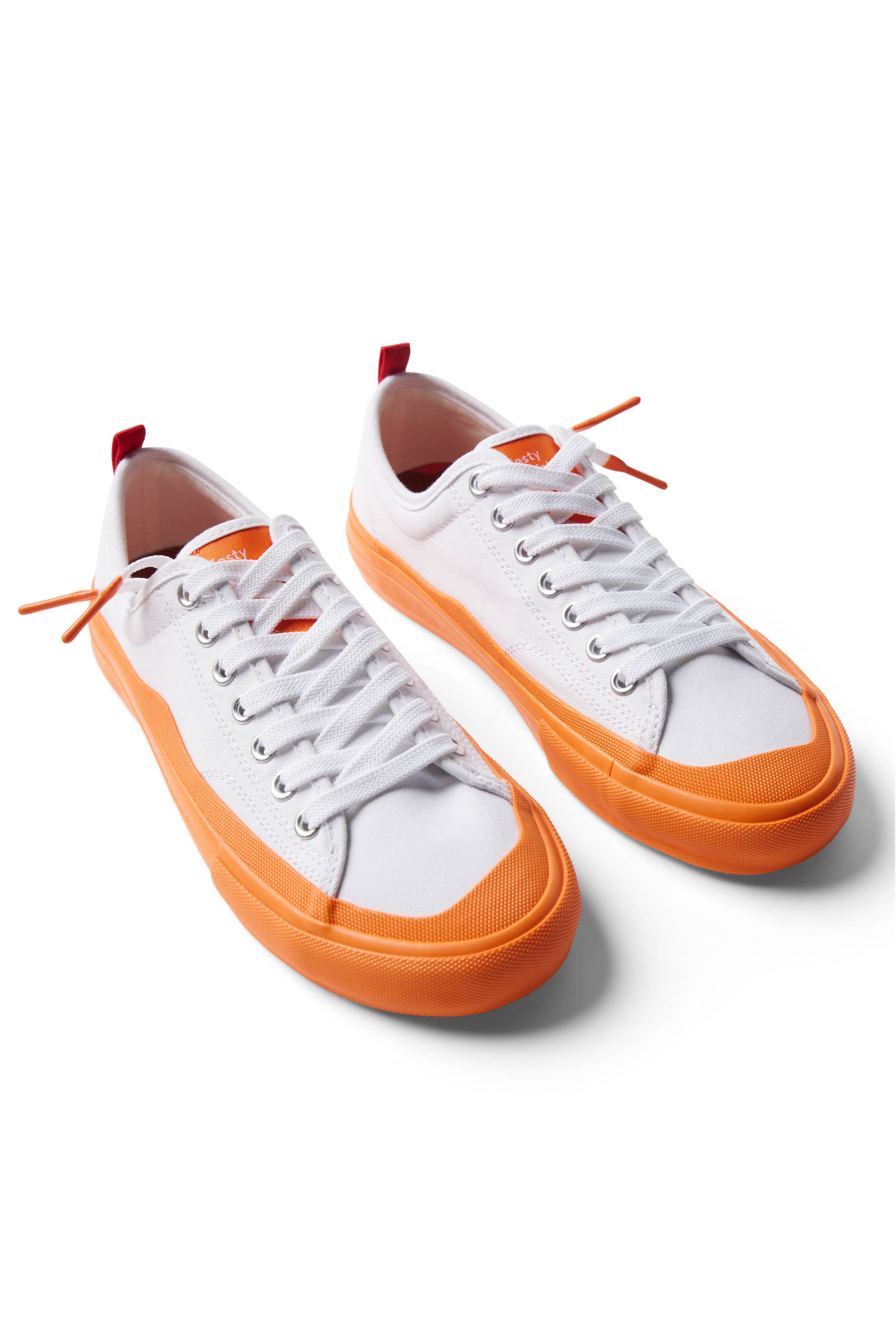 Pair of Dipped Kicks white shoes with orange soles