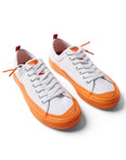 Pair of Dipped Kicks white shoes with orange soles