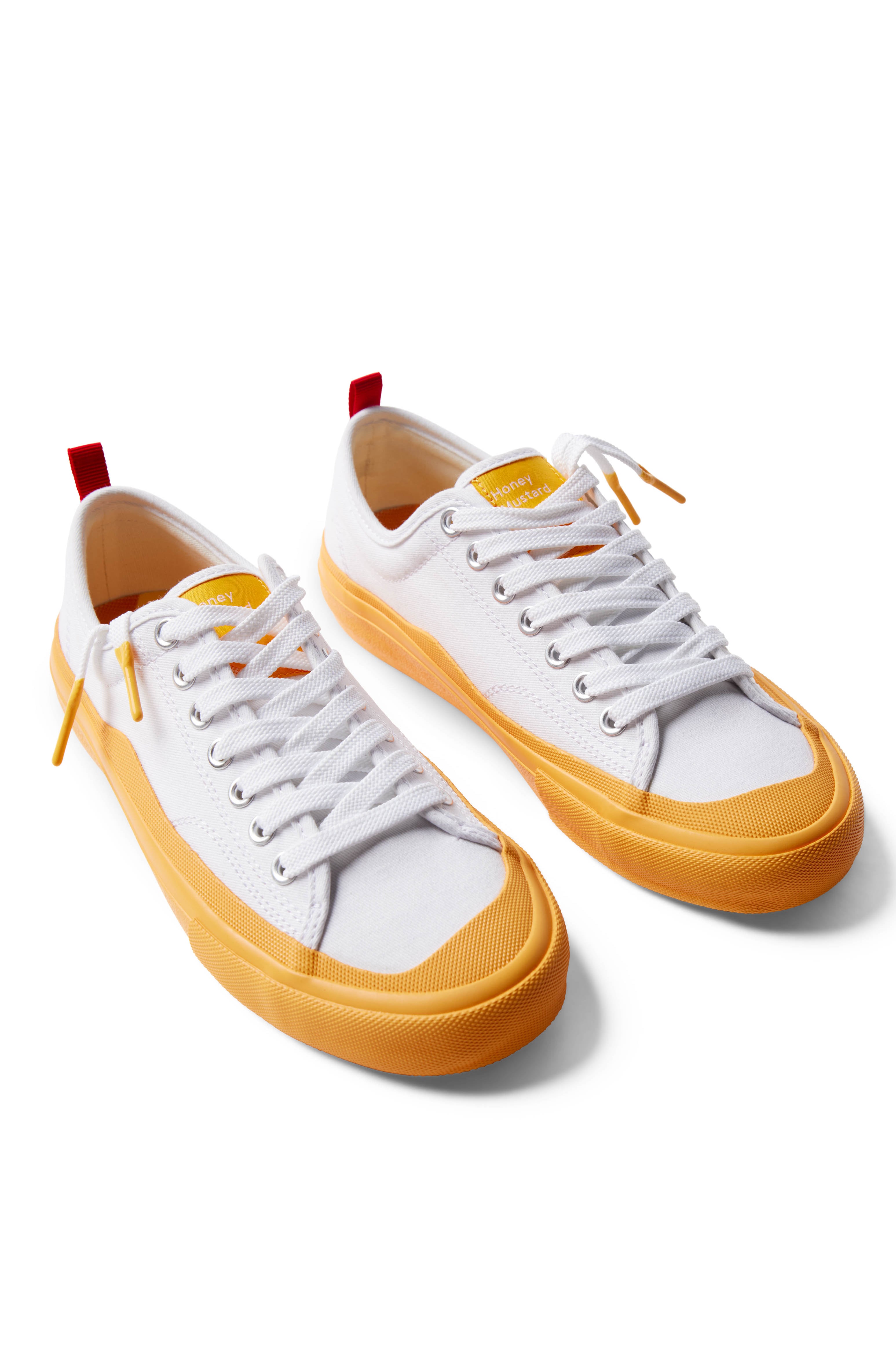 Pair of Dipped Kicks white shoes with yellow soles