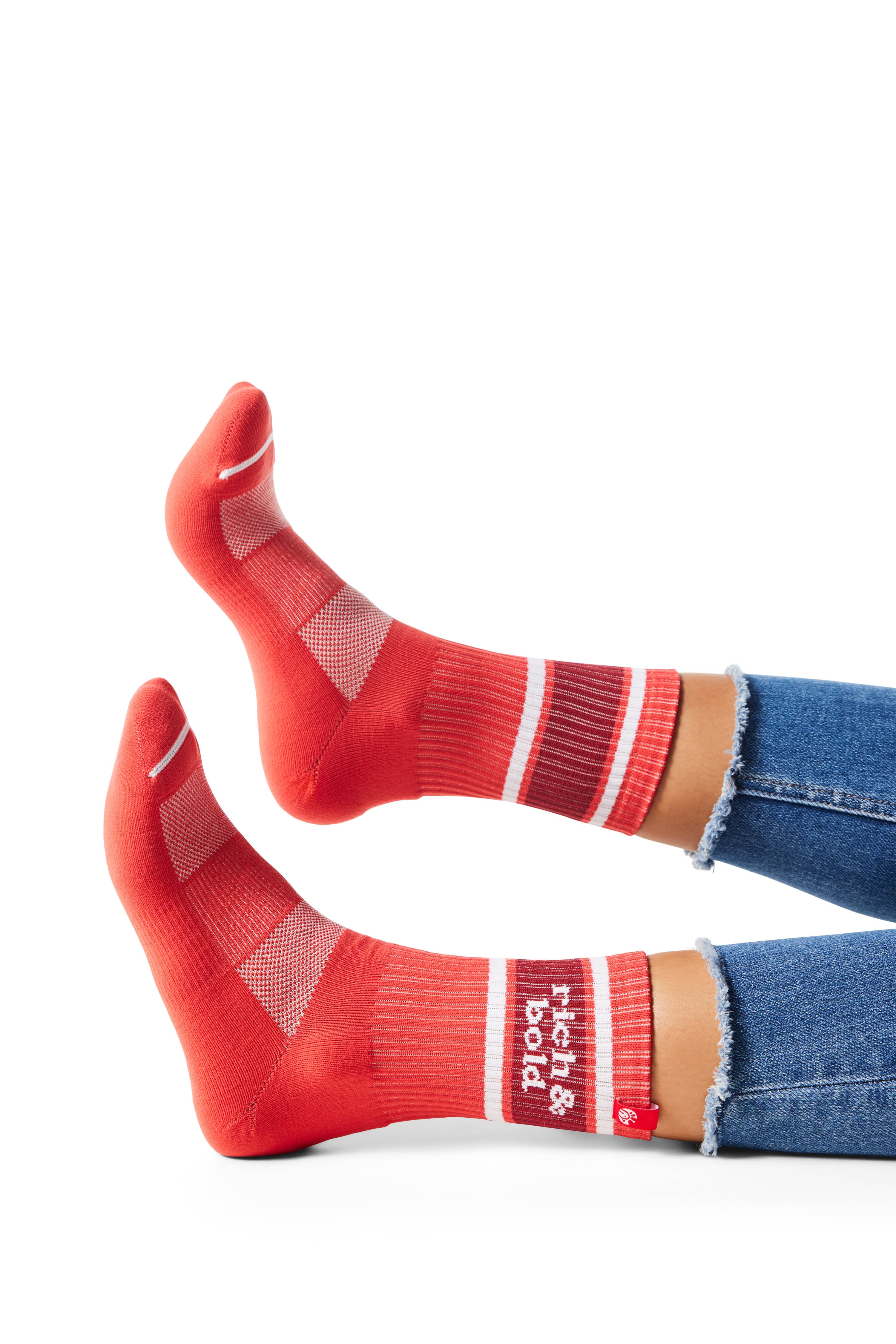 Pair of feet wearing red socks with text &quot;rich &amp; bold&quot; above ankle on sock