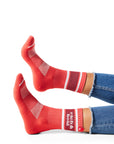 Pair of feet wearing red socks with text "rich & bold" above ankle on sock