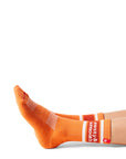 Pair of feet wearing orange socks with text "zesty & smooth" above ankle on sock