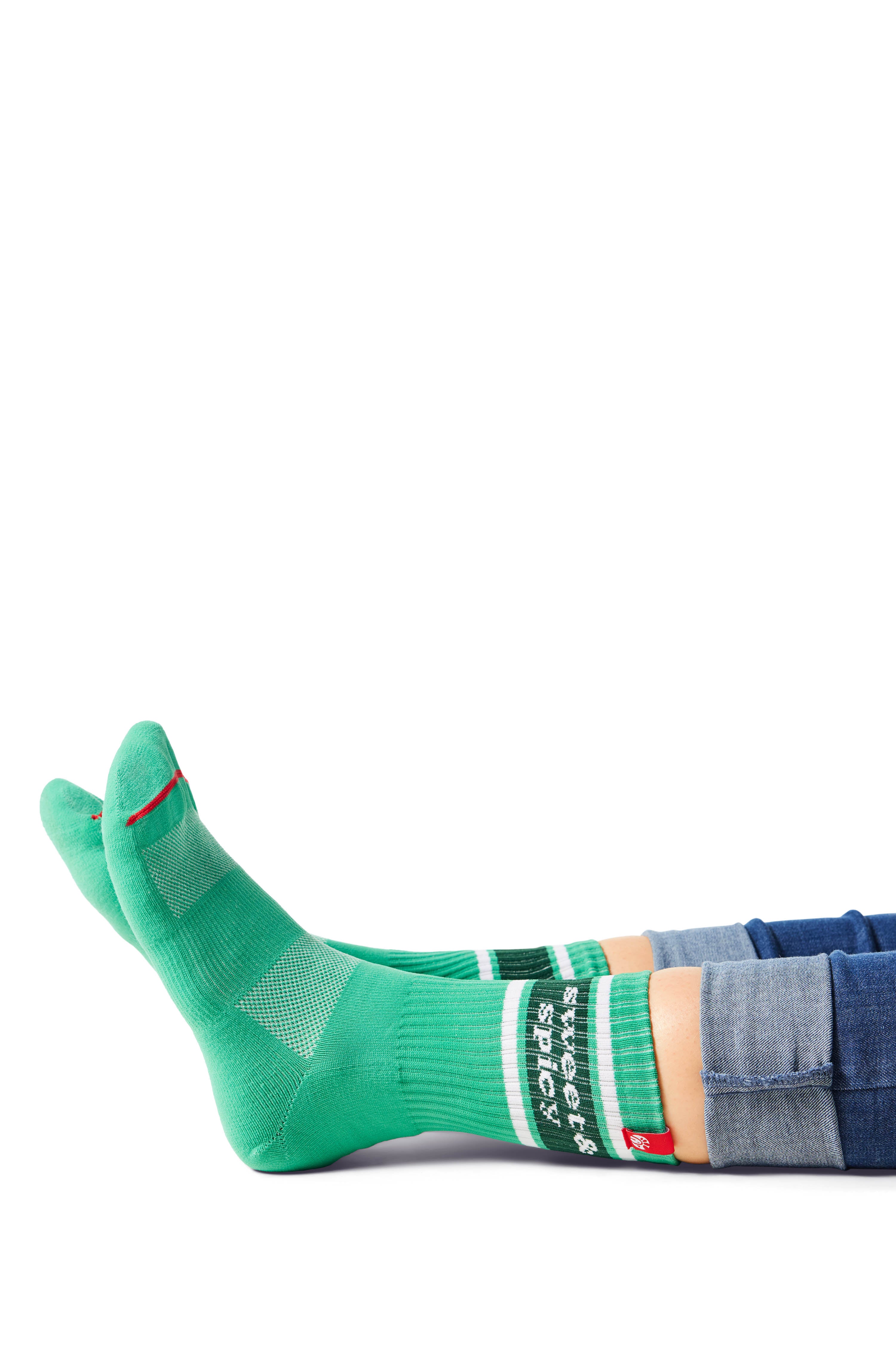 Pair of feet wearing green socks with text &quot;sweet &amp; spicy&quot; above ankle on sock