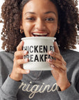 Girl wearing Original Crewneck holding Chicken for Breakfast Camper Mug up to her face