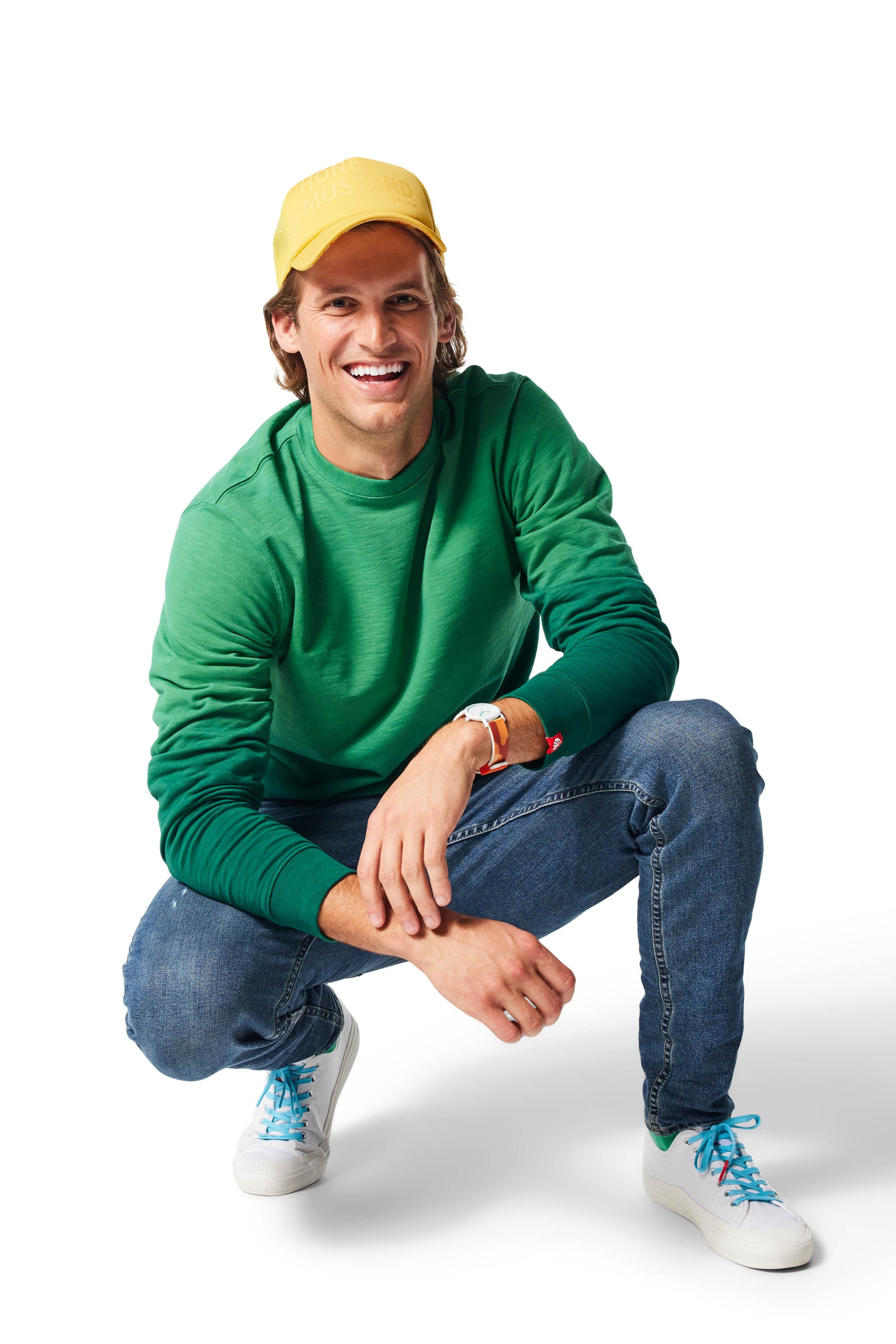 Man kneeling wearing green Ombre Crewneck with white Dipped Kicks shoes and blue Shoelaces