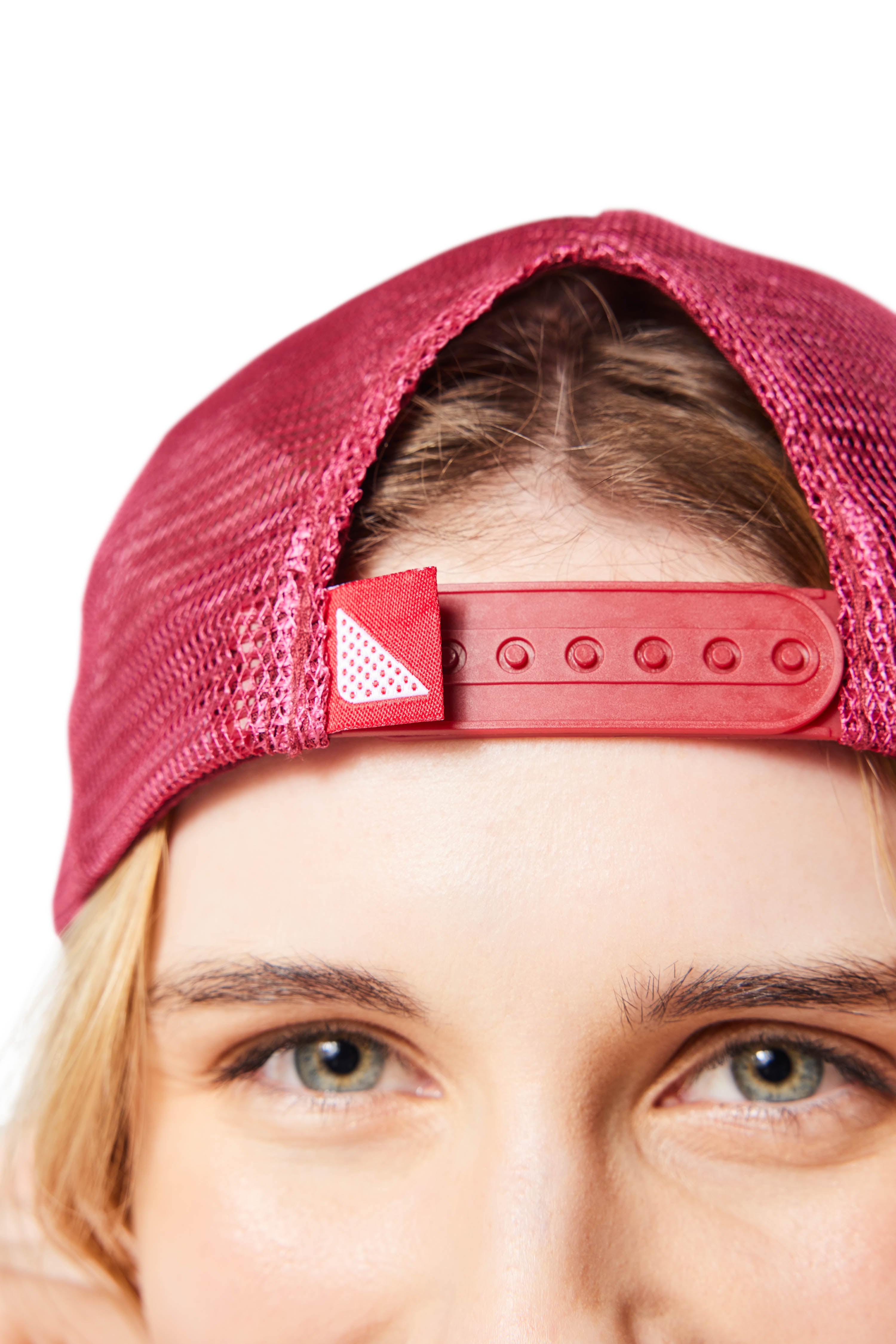 Closeup of woman's face wearing red Trucker Hat backwards showing snap closure