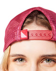 Closeup of woman's face wearing red Trucker Hat backwards showing snap closure