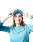 Blue Trucker Hat on woman with blonde hair holding hat and displaying tone-on-tone blue underbill