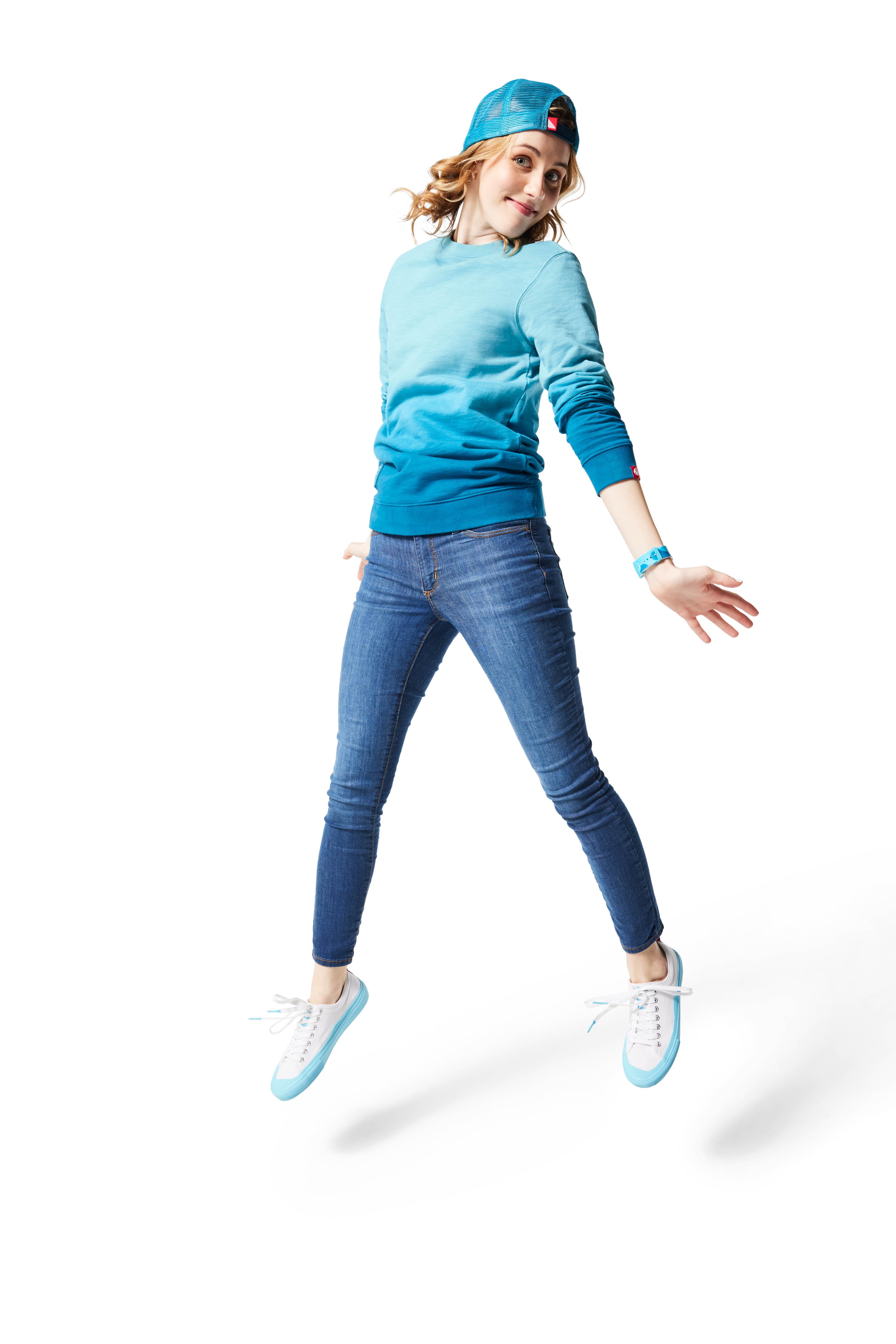 Woman jumping in air wearing blue Ombre Crewneck with blue Dipped Kicks and blue Trucker Hat