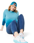 Woman sitting on ground wearing blue Ombre Crewneck with blue Dipped Kicks and blue Trucker Hat