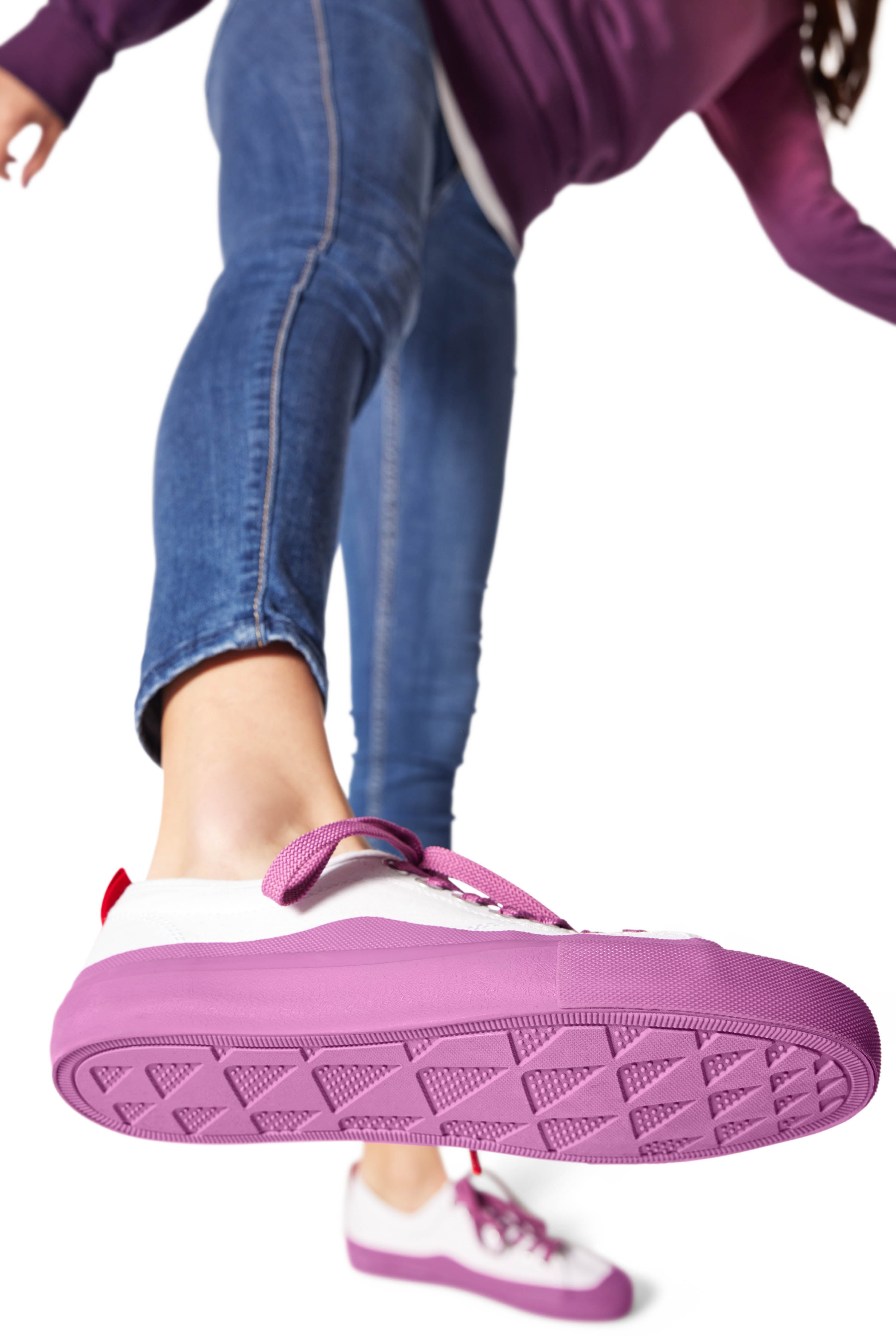 Shoe raised in mid-air displaying purple/Polynesian Sauce Dipped Kicks shoe tread with sauce packet dot pattern