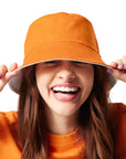 Orange/Zesty Buffalo Sauce Reversible Bucket Hat on girl with brunette hair