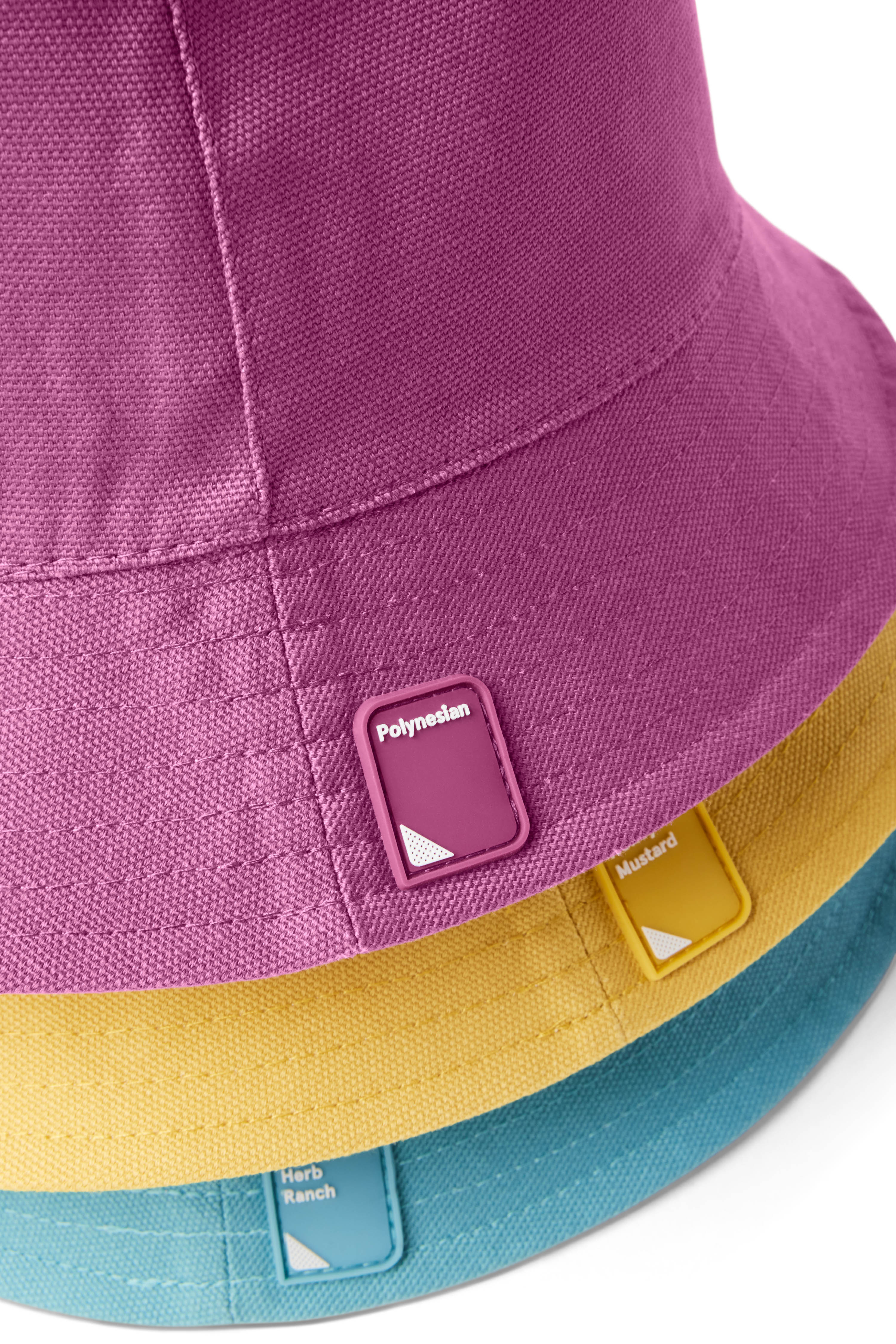 Closeup of yellow, gray/white, purple, and blue stack of Reversible Bucket Hats