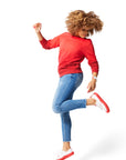 Woman jumping in air wearing red Ombre Crewneck with red Dipped Kicks shoes