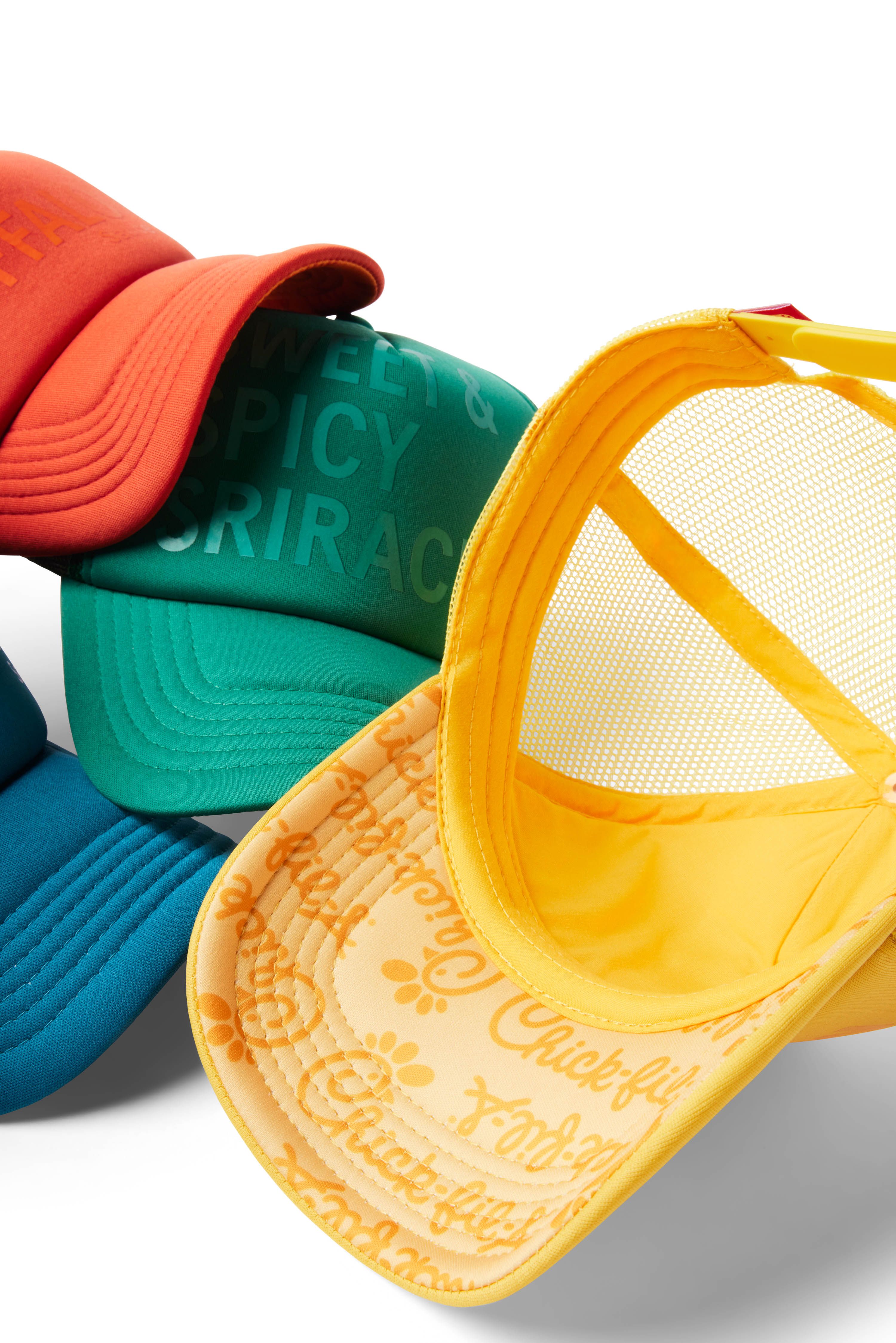 Several Trucker Hats including orange/ Buffalo, blue/Ranch, green, and yellow hat flipped over with logo printed under bill