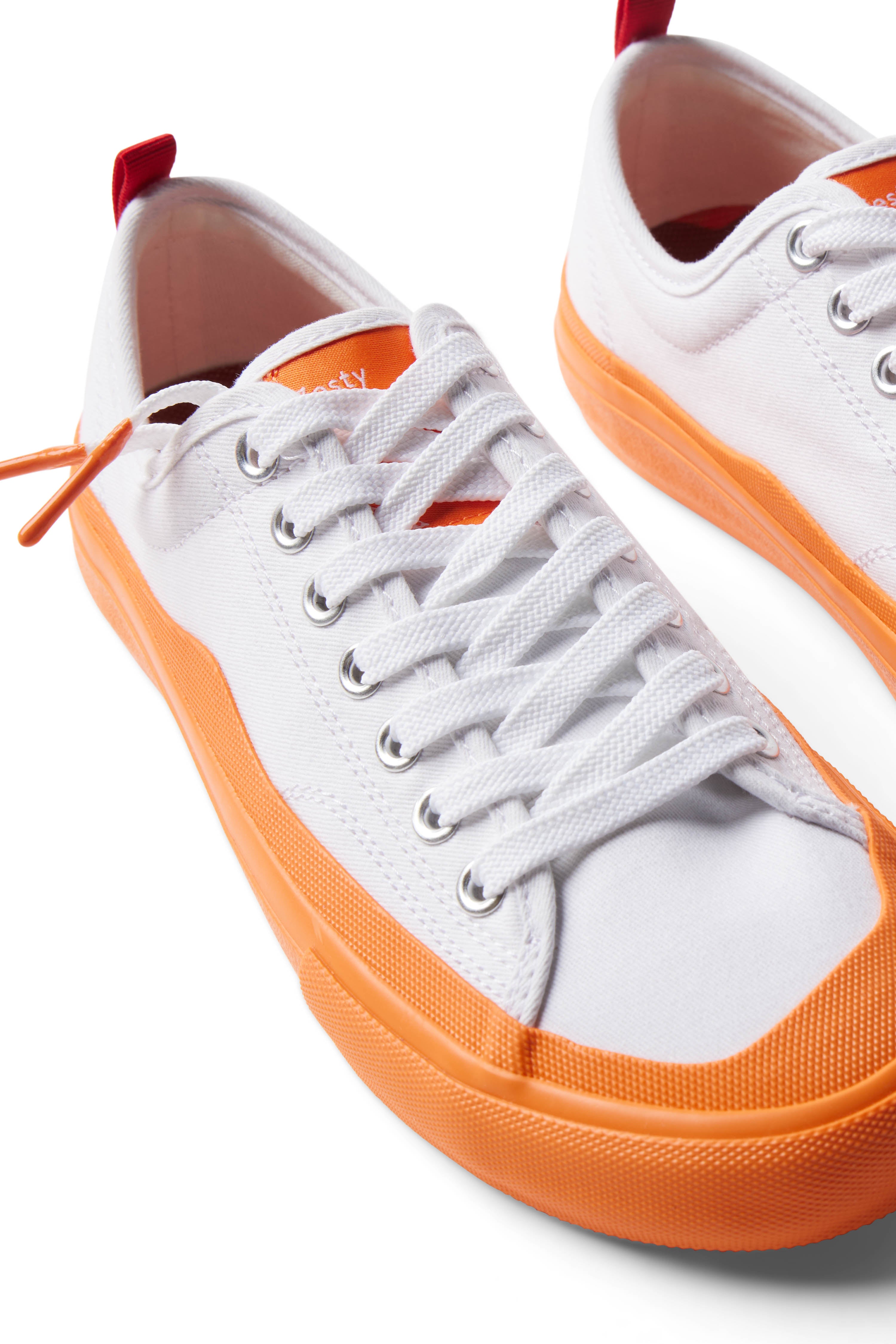 Pair of Dipped Kicks white shoes with orange soles