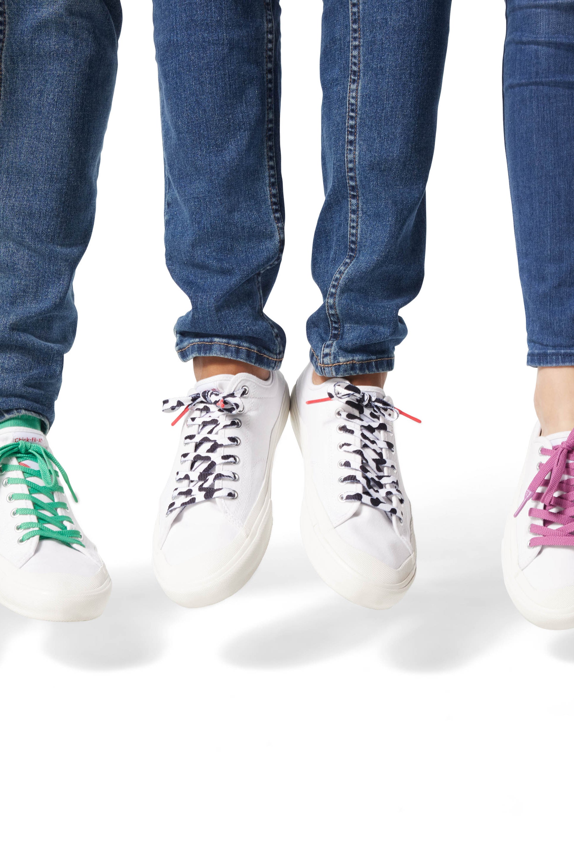 Three sets of Dipped Kicks shoes jumping in mid air displaying Sauce Shoelaces in green, cow print, and purple