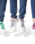 Three sets of Dipped Kicks shoes jumping in mid air displaying Sauce Shoelaces in green, cow print, and purple