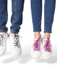 Two sets of Dipped Kicks shoes jumping in mid air displaying Sauce Shoelaces in purple and cow print