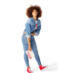 Woman standing and wearing jeans, denim jacket and white Classic Chick-fil-A® Tee and holding Classic Chick-fil-A™ Clutch