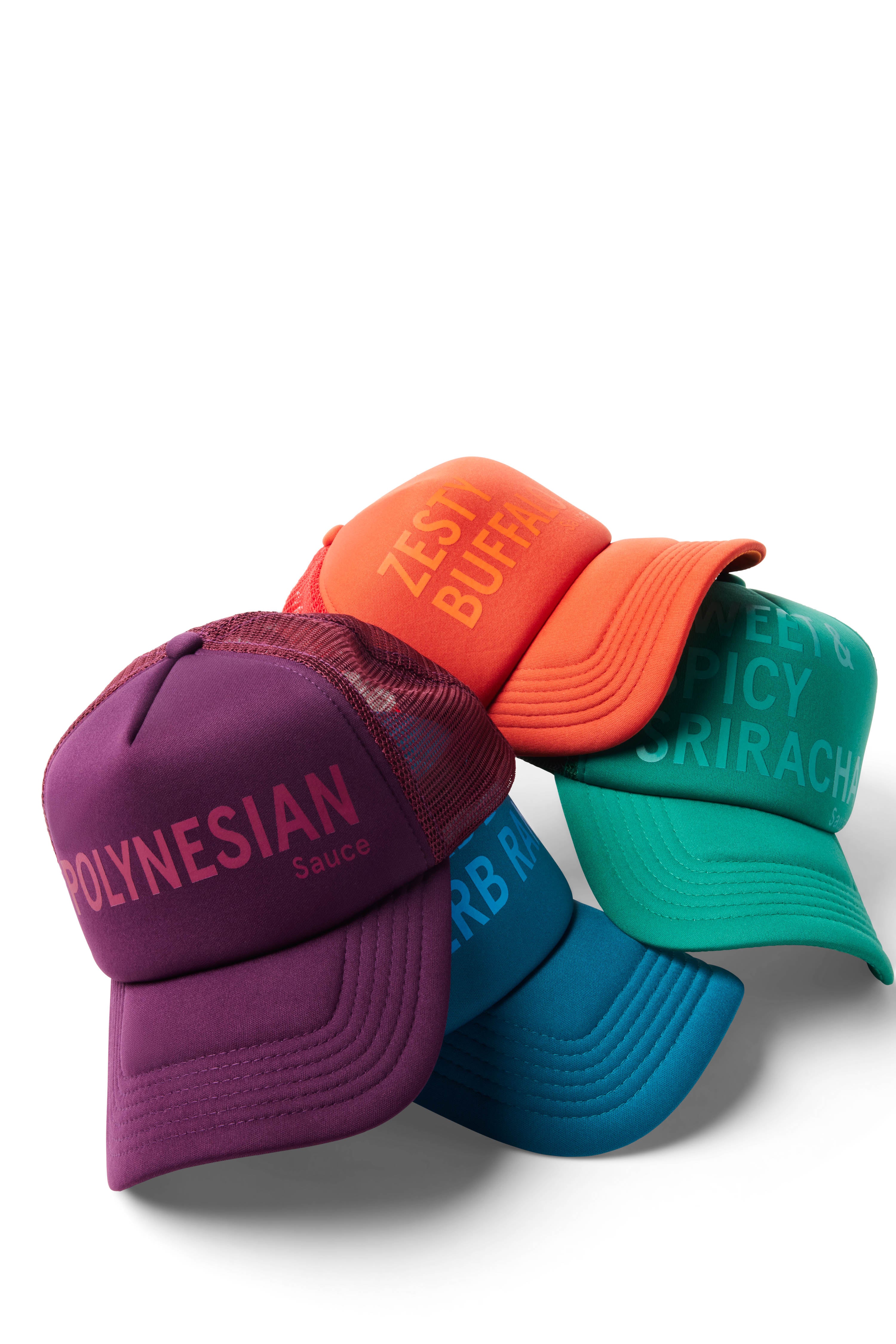 Stack of Sauce Trucker Hats including purple/Polynesian, orange/Zesty Buffalo, blue/Ranch, and green/Sriracha