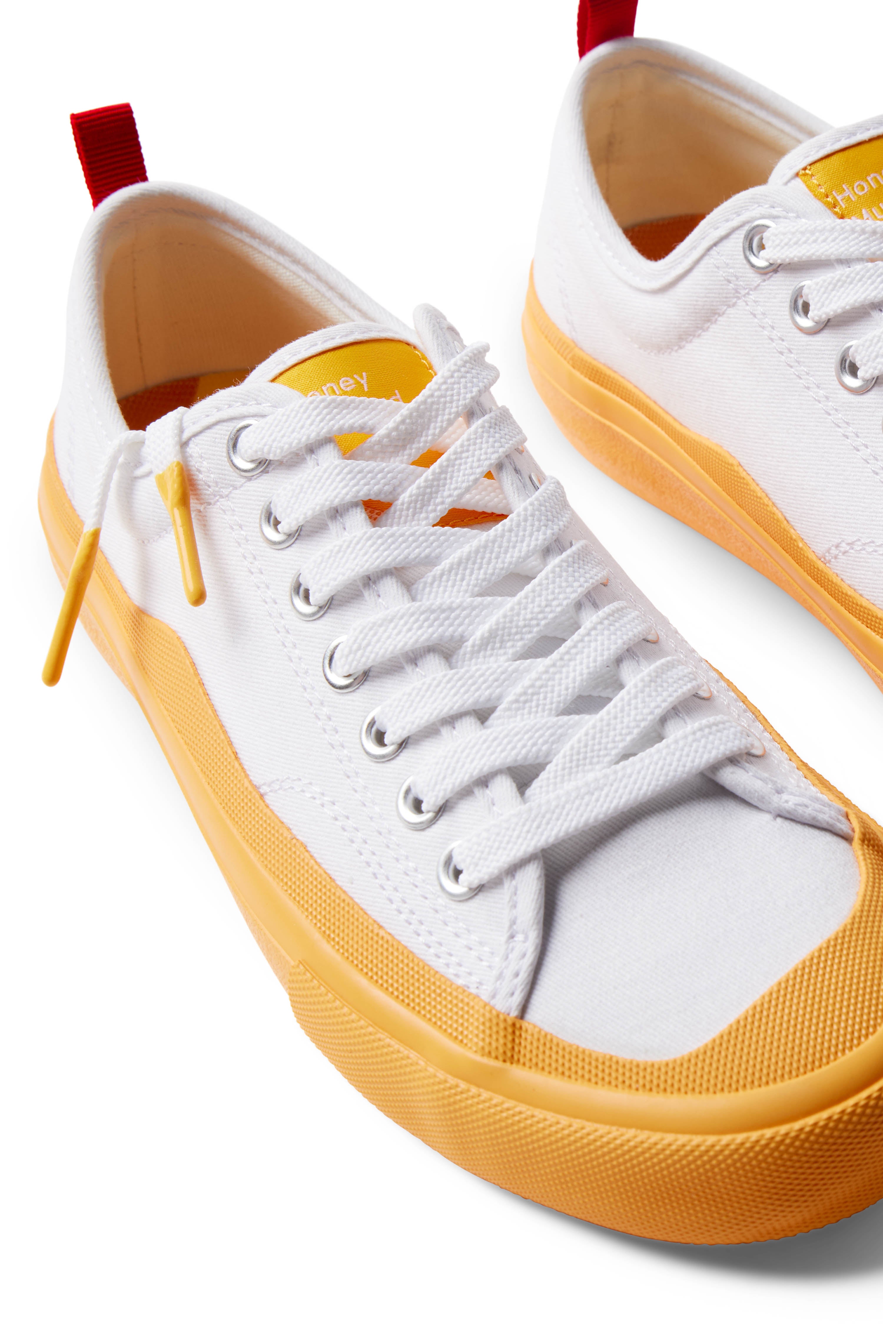 Pair of Dipped Kicks white shoes with yellow soles